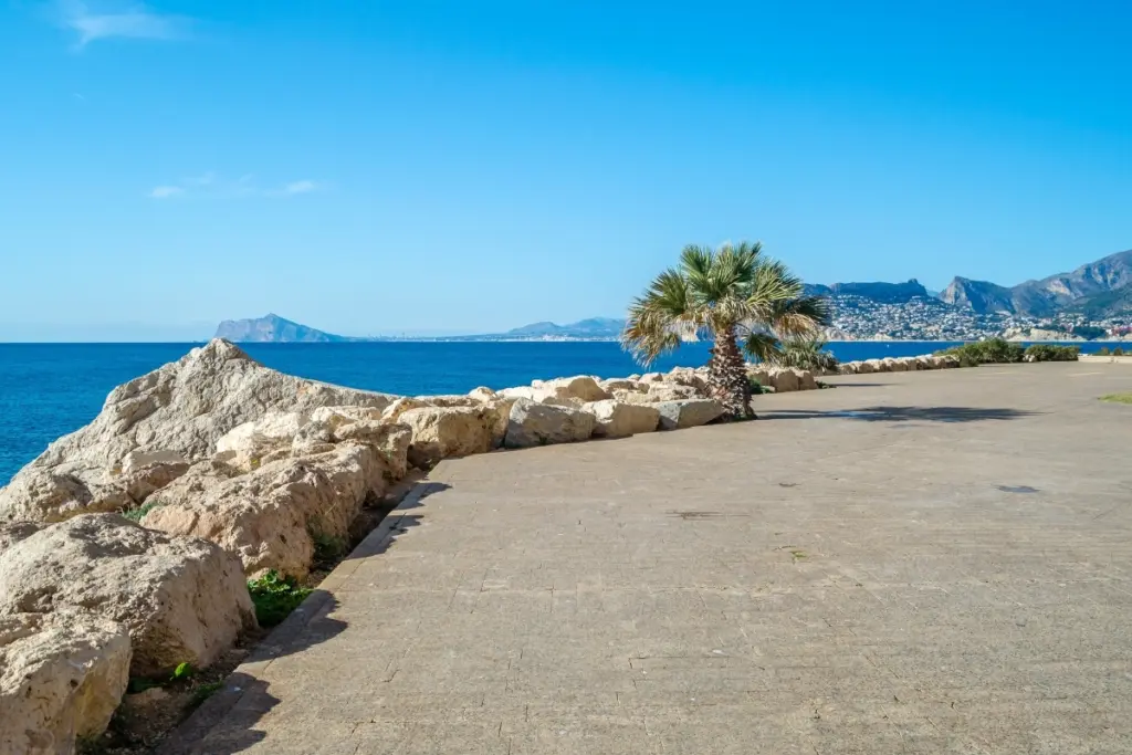 Paseo Princesa de Asturias coastal walking path in Calpe with palm trees and mountain views