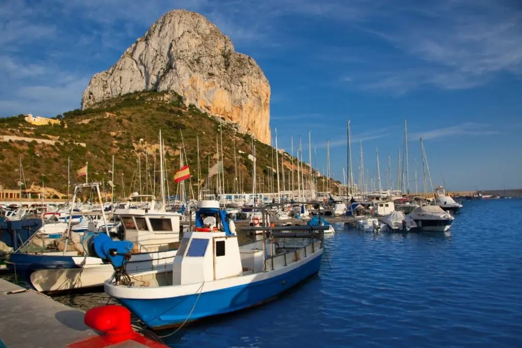Fishing boats in Calpe port with the Peñón de Ifach rising behind them.