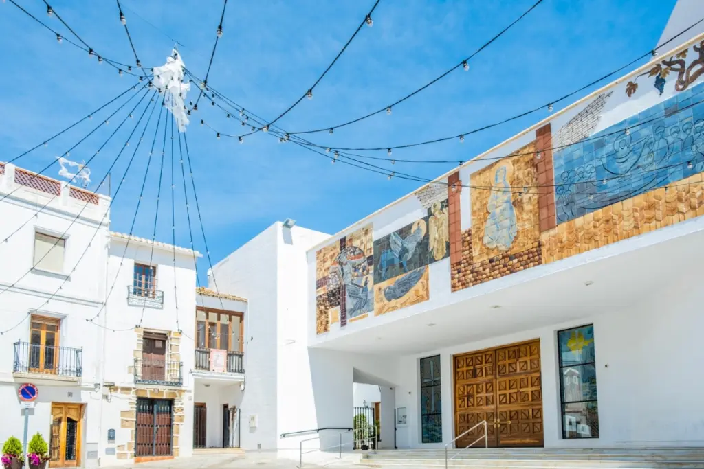 Church and ceramic murals in Calpe Old Town beneath summer lights