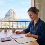 Woman preparing NIE application documents in Calpe with the Peñón de Ifach behind her