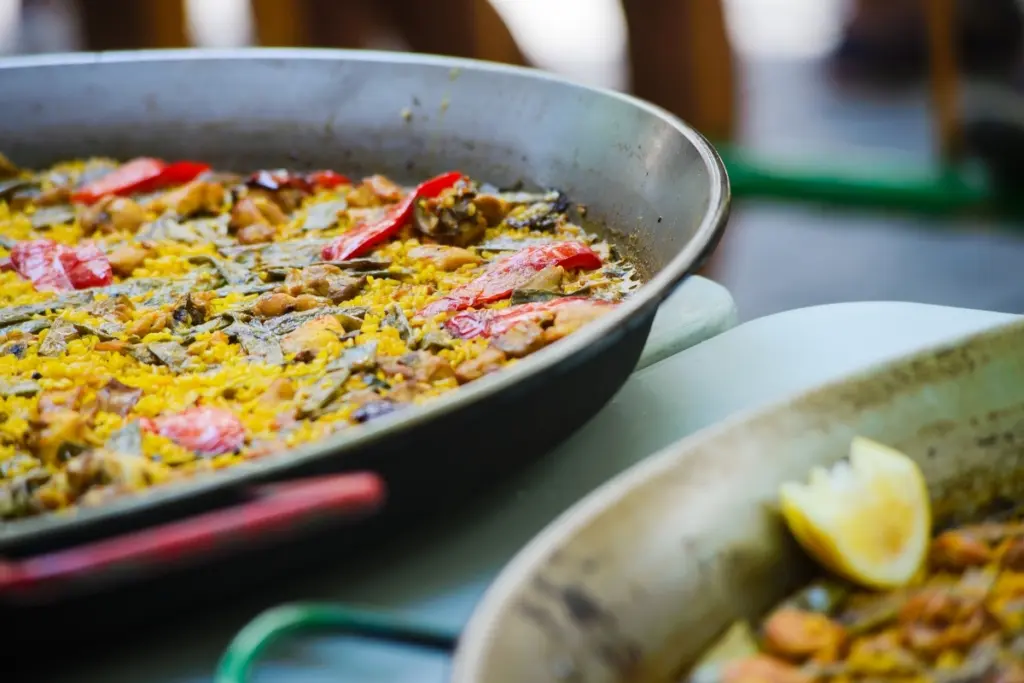 Close-up of paella valenciana in a traditional pan, with saffron rice, red pepper and chicken