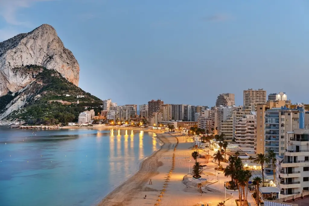 La Fossa Beach in Calpe at dusk with the Peñón de Ifach and illuminated seafront